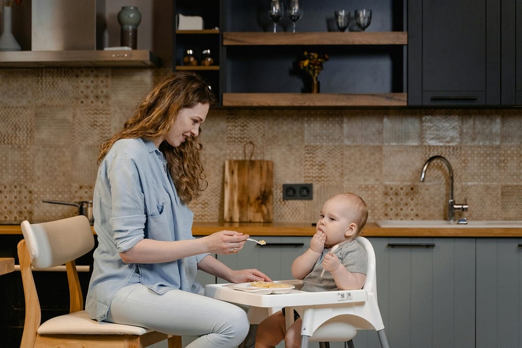 Une mère nourrit son bébé avec amour dans une cuisine moderne. Un moment familial réconfortant.
